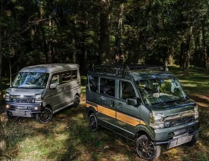 Two lifted off-road Suzuki Every DA64V vans in a forest